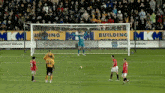 a soccer game is being played in front of a building mkm banner
