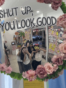 a mirror that says shut up you look good is surrounded by pink flowers
