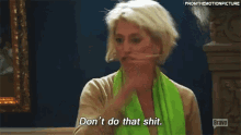 a woman wearing a green scarf and a tan sweater is talking to someone .