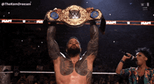 a man is holding a wrestling championship belt over his head while a woman sings into a microphone