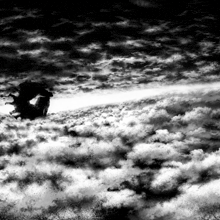 a black and white photo of a cloudy sky with a person standing in the middle