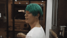 a man with green hair is standing in front of a window with the letter d on the bottom