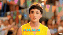 a young man in a yellow shirt is standing in front of a crowd .