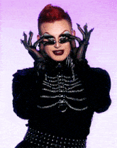 a drag queen wearing a black outfit and gloves covering her eyes with her hands