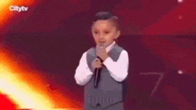 a young boy is standing on a stage holding a microphone .