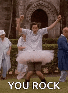 a man is wearing a tutu and dancing in a park with a group of people .