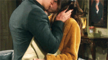 a man and a woman are kissing in front of a picture of a man in a suit