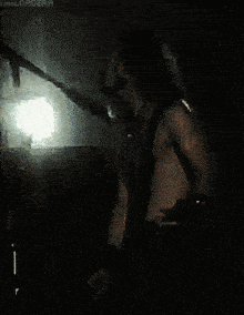 a man without a shirt is standing in front of a microphone in a dark room ..