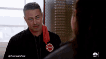 a man wearing a chicago fire department jacket talking to a woman