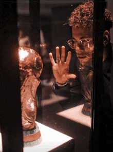 a man wearing glasses looks at a trophy in a display case