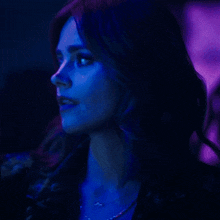 a close up of a woman 's face with a purple light behind her