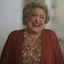 an elderly woman is laughing and wearing a necklace with a star on it