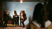 a group of women are dancing in front of a wall