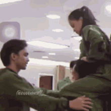 a man is carrying a woman on his shoulders while another man looks on .