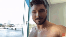 a shirtless man is standing in front of a window with a red arrow pointing to the left that says ' a '
