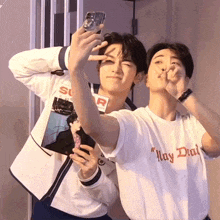 a man wearing a shirt that says may dial takes a selfie
