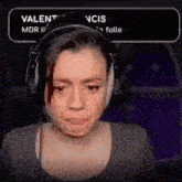 a woman wearing headphones is making a funny face in front of a sign that says valent