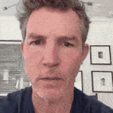 a close up of a man 's face with a beard and a blue shirt