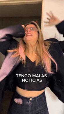 a woman wearing sunglasses and a black crop top with the words tengo malas noticias on it