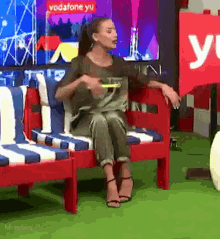 a woman sits on a red couch in front of a vodafone sign