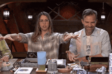 a man and a woman are sitting at a table and the woman is wearing a shirt that says " best company "