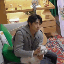 a man is sitting on a couch holding a white dog .