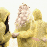 a woman in a yellow raincoat is standing next to another woman in a yellow raincoat .