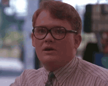 a man wearing glasses and a striped shirt is looking at the camera