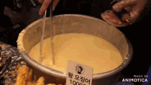a bowl of sauce with tongs and a sign that says made in animotica