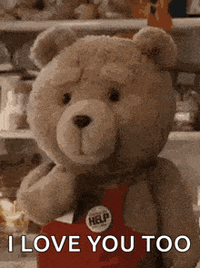 a teddy bear wearing a red apron and a button that says i love you too .