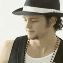 a close up of a man wearing a black hat and a white ribbon .