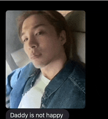 a man in a denim jacket is sitting in a car and daddy is not happy .