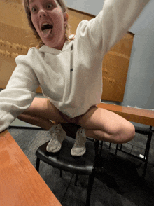 a woman sitting on a chair with her legs crossed and her tongue hanging out