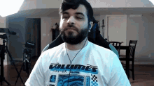 a man with a beard wearing a volumes shirt
