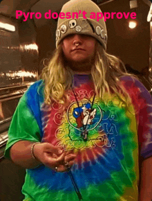 a man wearing a tie dye shirt and a beanie is smoking a cigarette