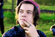 a young man wearing a pink hat and a plaid shirt is thinking