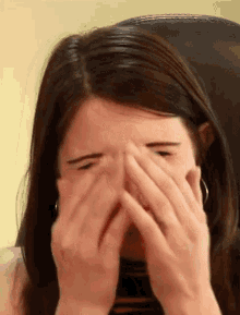 a close up of a woman covering her face with her hands .