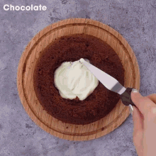 a person is spreading frosting on a chocolate cake