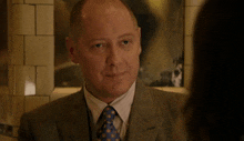 a man in a suit and tie smiles while looking at a woman