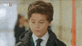 a young boy in a suit and tie with trt1 written on the bottom