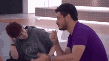 a man in a purple shirt is sitting next to a woman in a gray sweatshirt with the word ito on it
