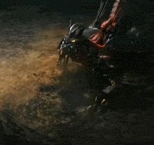 a red and black robot is laying on the ground in the dark