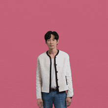 a man wearing a white jacket and blue jeans is standing with his arms outstretched