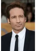 a man wearing a suit and tie is smiling for the camera