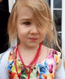 a little girl wearing a colorful floral dress and a red necklace