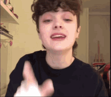 a woman with curly hair is wearing a black shirt and giving a thumbs up