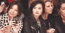 a group of women sitting in a row at a fashion show .