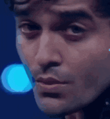 a close up of a man 's face in front of a blue light