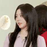 a woman with long black hair is wearing a pink shirt and has a microphone in her mouth .