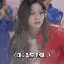 a woman wearing glasses and a red jacket is talking in a foreign language .